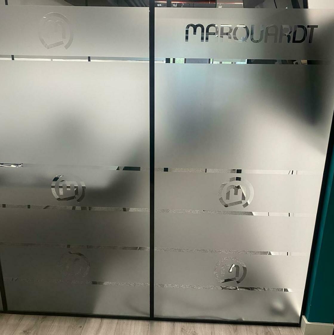 Aplicare folie sablată personalizată în birourile companiei Marquardt, design elegant și profesional pentru ambient interior.