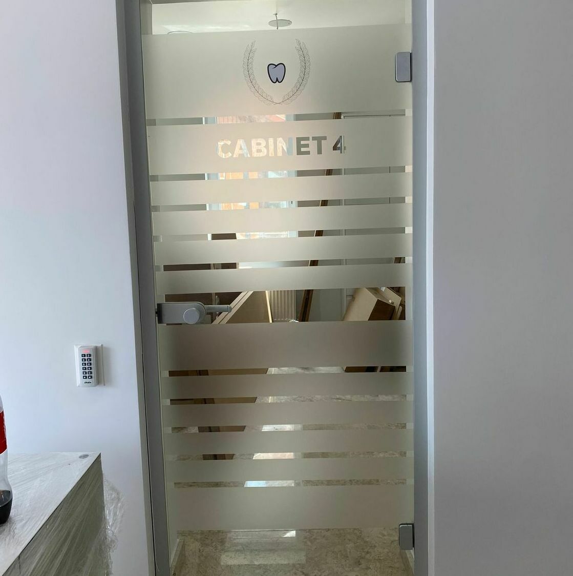 Decorarea geamului pentru cel mai mare cabinet stomatologic din Sibiu cu folie sablată aplicată, design interior profesional și elegant.